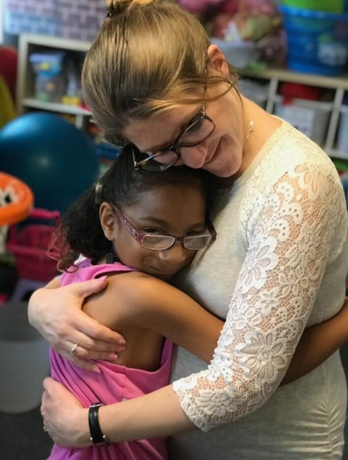 Devra hugging a young client during a therapy session.